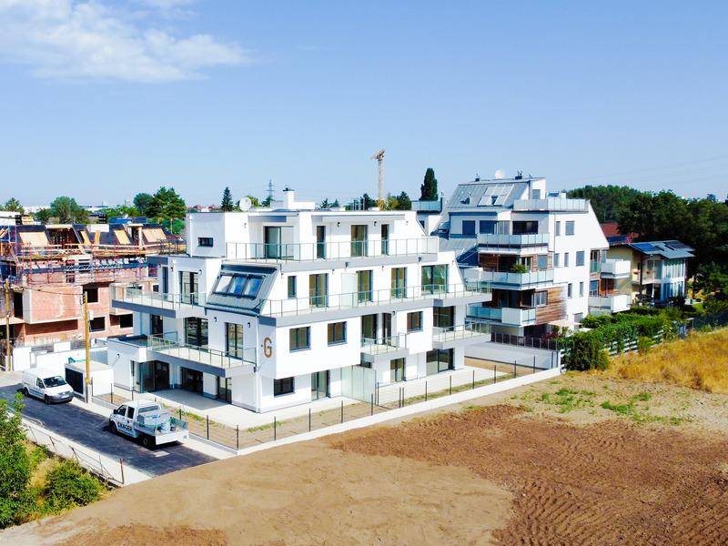 Neubau-Wohngebäude mit moderner Architektur, großen Balkonen und umliegender Baustelle.