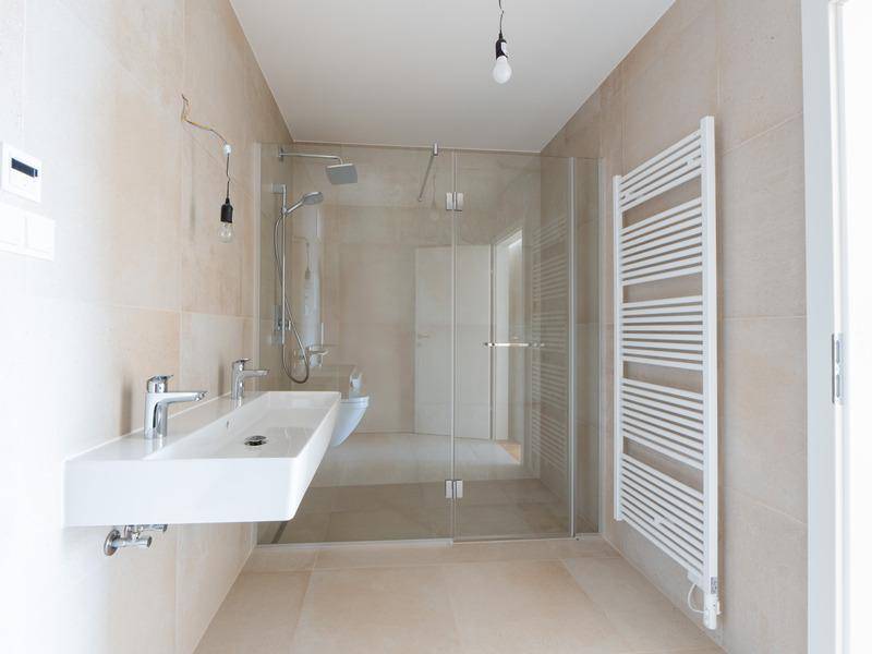 Modernes Badezimmer mit begehbarer Dusche, Doppelwaschbecken und beheiztem Handtuchhalter.