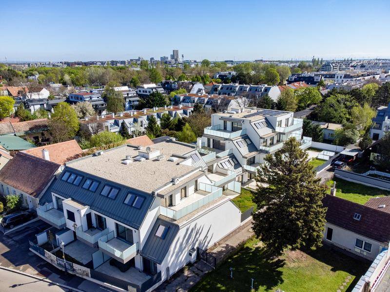 Weitläufige Luftaufnahme eines modernen Wohnkomplexes in einer grünen, städtischen Umgebung.