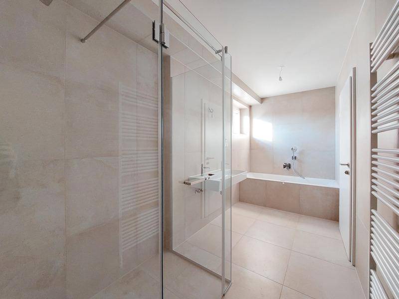 Modernes Badezimmer mit begehbarer Dusche, Badewanne und beheiztem Handtuchhalter.