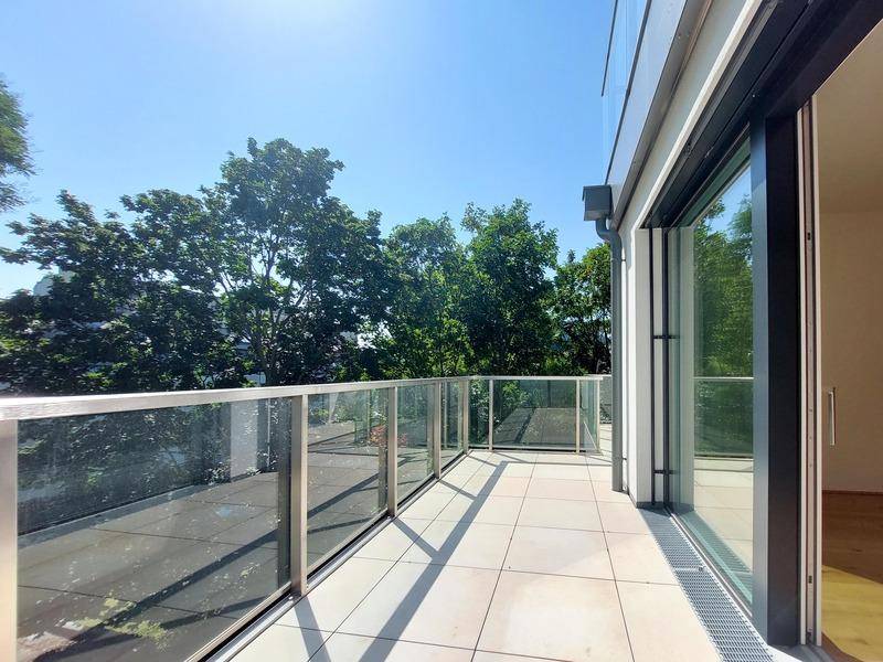 Geräumiger Balkon mit Glasgeländer und Blick ins Grüne, ideal zum Entspannen.
