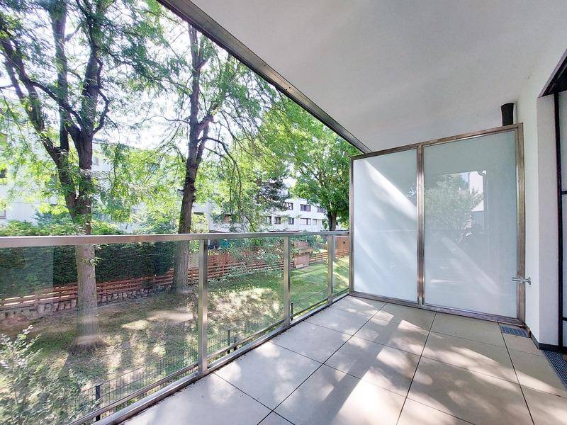 Geräumiger Balkon mit Glasgeländer und üppigem Grünblick, ideal zum Entspannen im Freien.