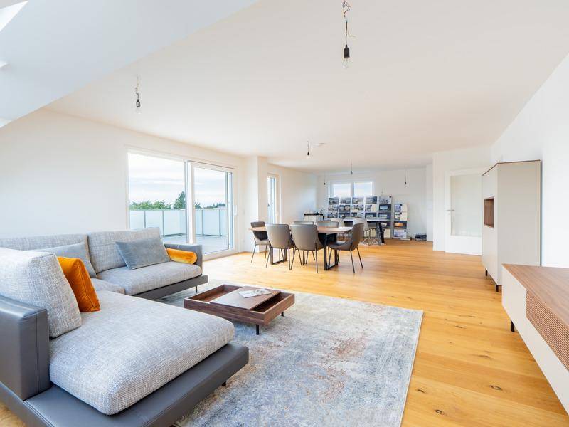 Helles, offenes Wohn-Esszimmer mit Holzboden und Zugang zu einer großen Terrasse.