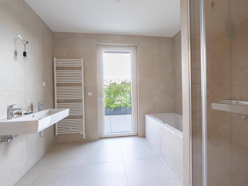 Helles Badezimmer mit Badewanne, Doppelwaschbecken und beheiztem Handtuchhalter.