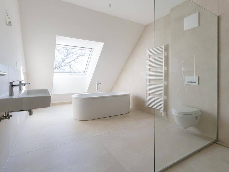 Modernes Badezimmer mit freistehender Badewanne, großer Dusche und Dachfenster für natürliches Licht.