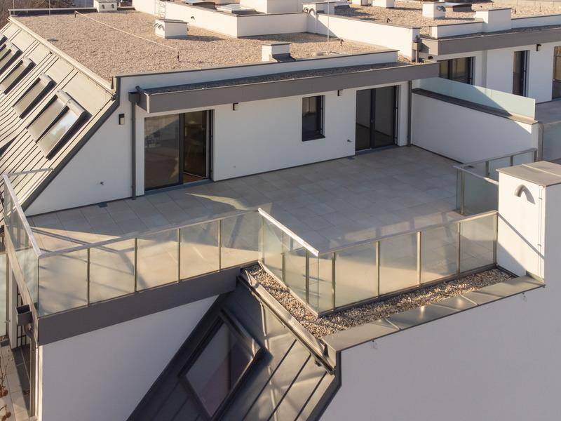 Weitere Ansicht der modernen Dachterrasse mit Glasbrüstung und Zugang zu den Innenräumen.