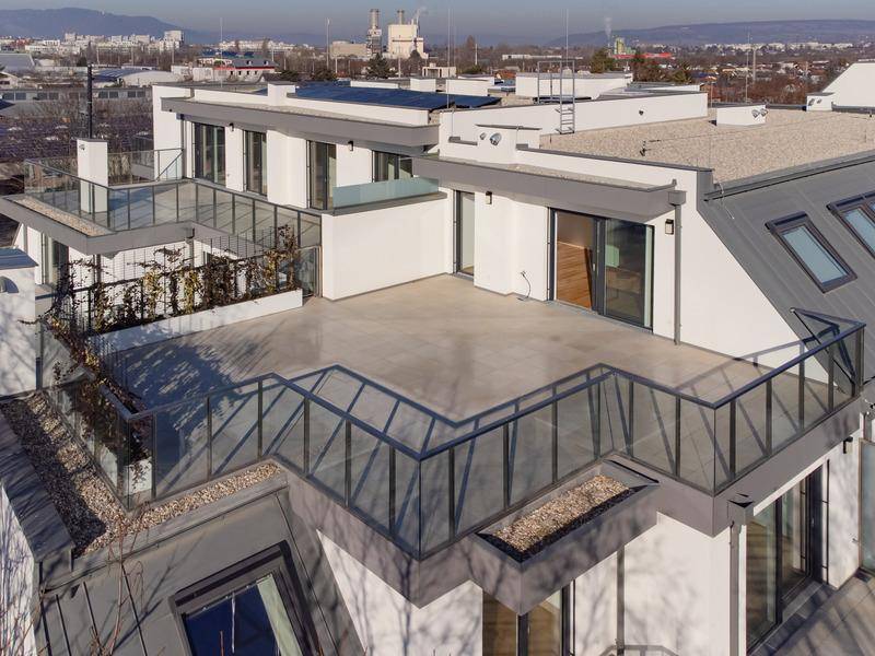 Großzügige Dachterrasse mit Glasgeländer und Blick auf die Stadt, ideal für Entspannung im Freien.