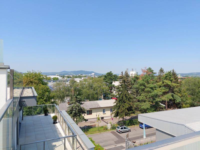 Sonniger Terrassenbereich mit Blick auf die grüne Umgebung und die umliegende Stadtlandschaft.