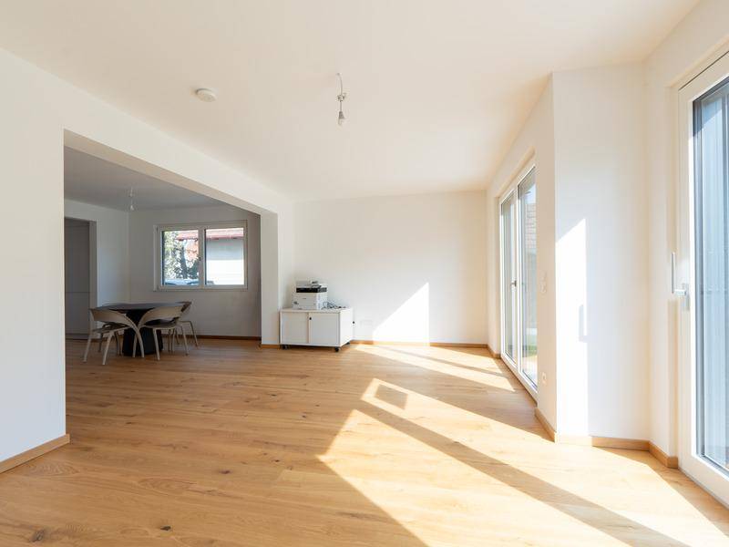 Lichtdurchfluteter Wohn- und Essbereich mit Holzboden und großen Schiebetüren zum Garten.