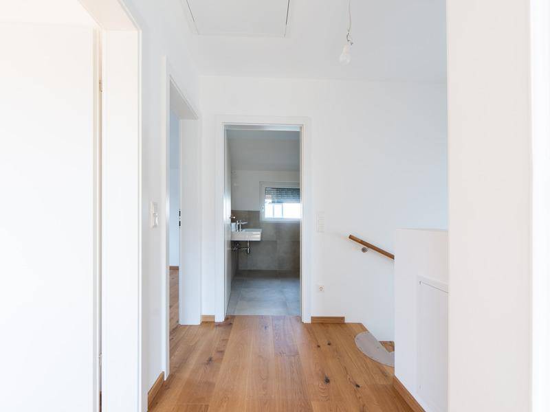Heller Flur mit Holzboden und Zugang zu weiteren Räumen im Obergeschoss.