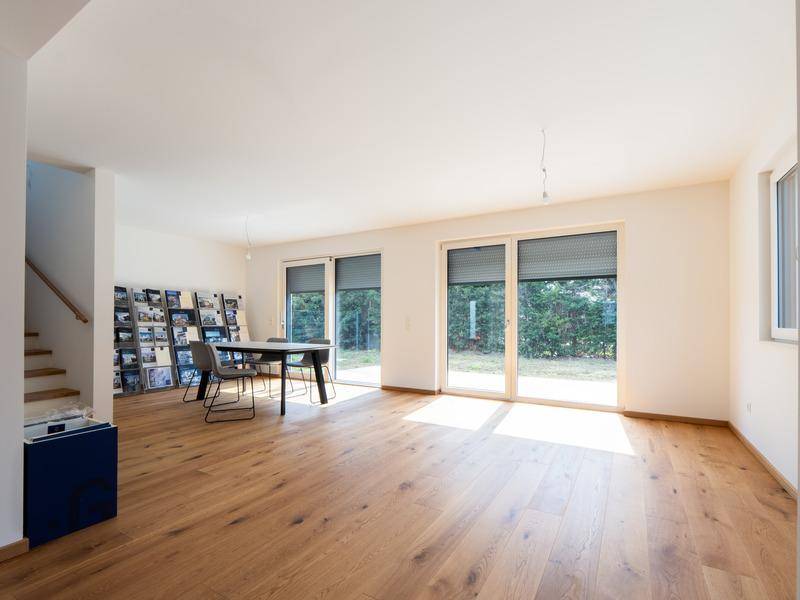 Heller, offener Wohn- und Essbereich mit Holzboden und Zugang zum Garten.