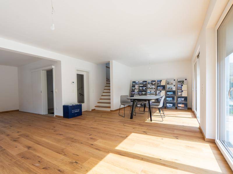 Geräumiger Wohnbereich mit Holzboden, Treppenzugang und viel Tageslicht.