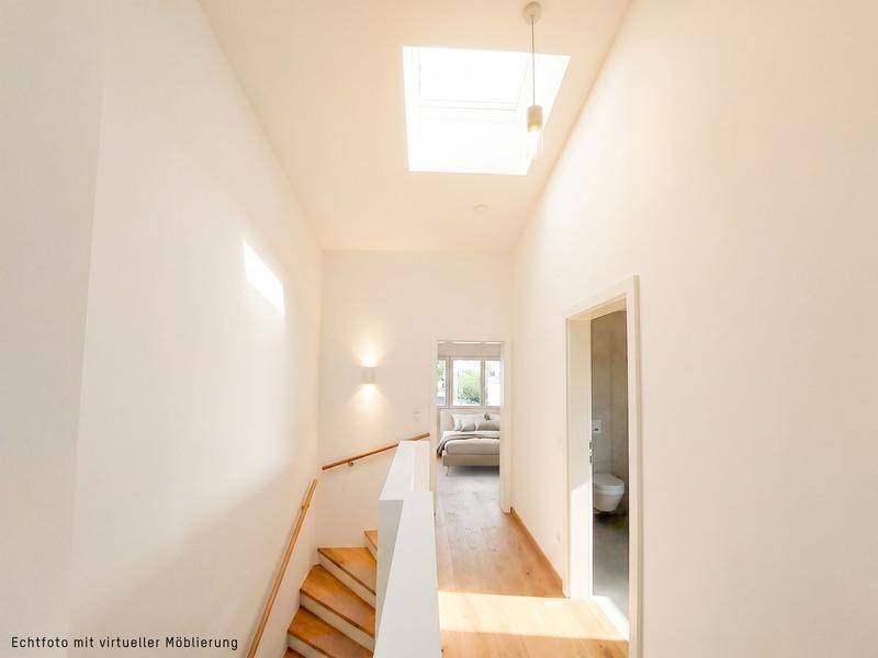 Heller Flur mit Holztreppe, Oberlicht und Zugang zu weiteren Räumen.