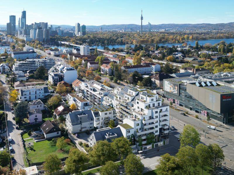 Luftaufnahme eines modernen Wohnkomplexes mit Blick auf die Stadt, Donau und umliegende Grünflächen.