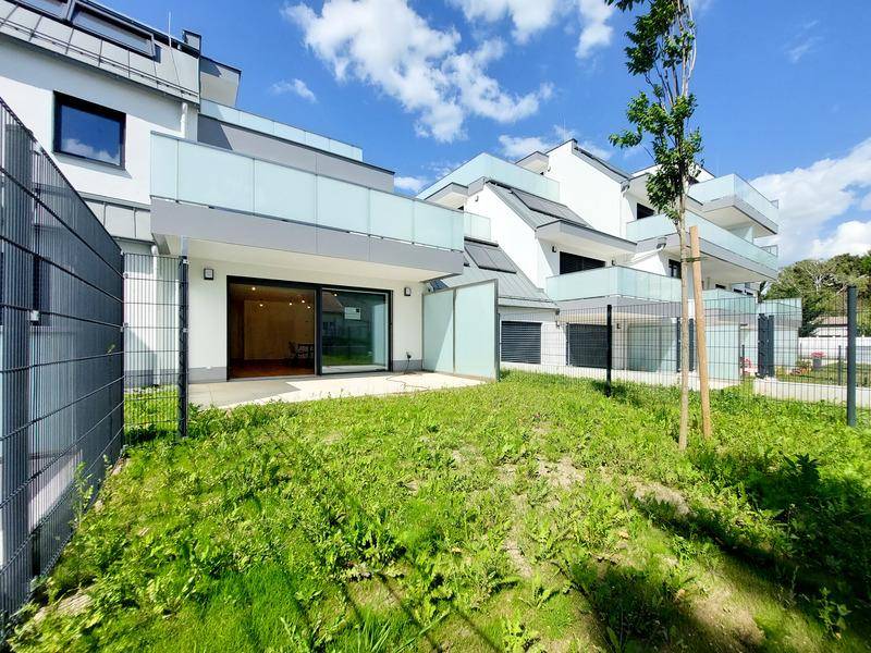 Erdgeschosswohnung mit privater Terrasse und kleinem Gartenbereich, umgeben von einem Zaun.