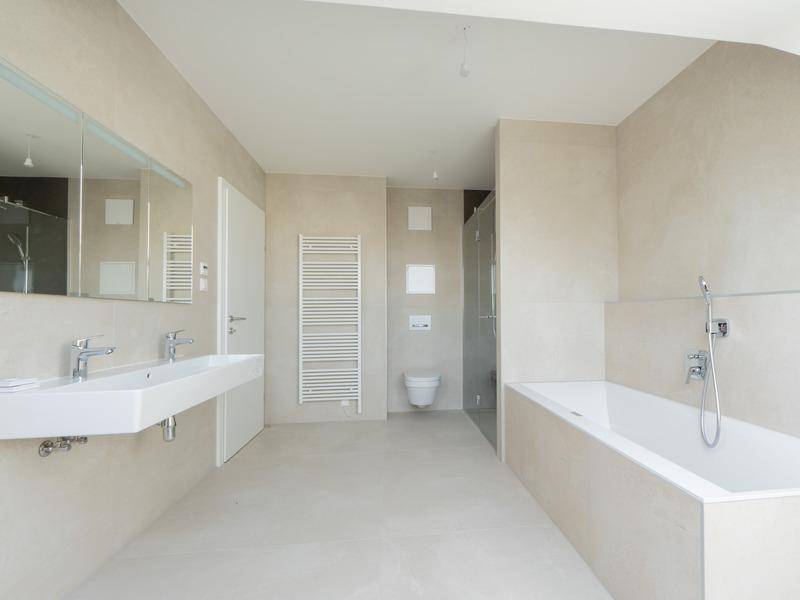 Geräumiges modernes Badezimmer mit Doppelwaschbecken, Badewanne, Dusche und beheiztem Handtuchhalter.