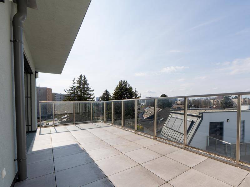 Große, sonnige Dachterrasse mit Fliesenboden und Glasgeländer bietet einen weiten Blick.