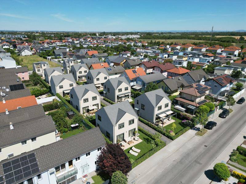 Luftaufnahme einer neuen Wohnsiedlung mit modernen Einfamilienhäusern und grünen Gärten.