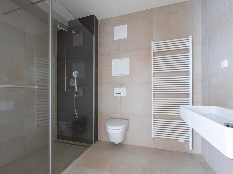 Modernes Badezimmer mit ebenerdiger Dusche, Wand-WC und beheiztem Handtuchhalter.