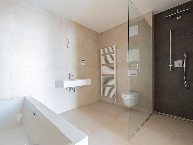 Modernes Badezimmer mit Badewanne, ebenerdiger Dusche und beheiztem Handtuchhalter.