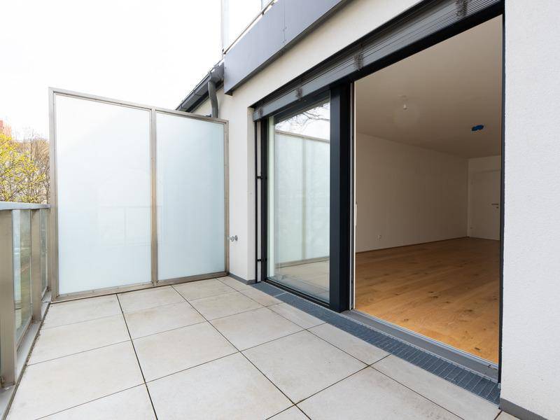 Geräumiger Balkon mit Fliesenboden und Schiebetür zum Innenbereich der Wohnung.