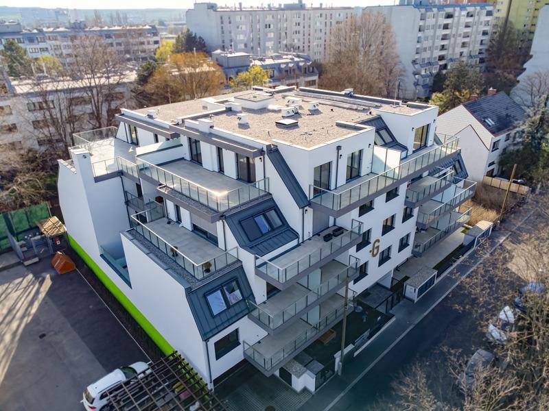 Luftaufnahme einer modernen Wohnanlage mit gestuften Balkonen und großzügigen Dachterrassen.