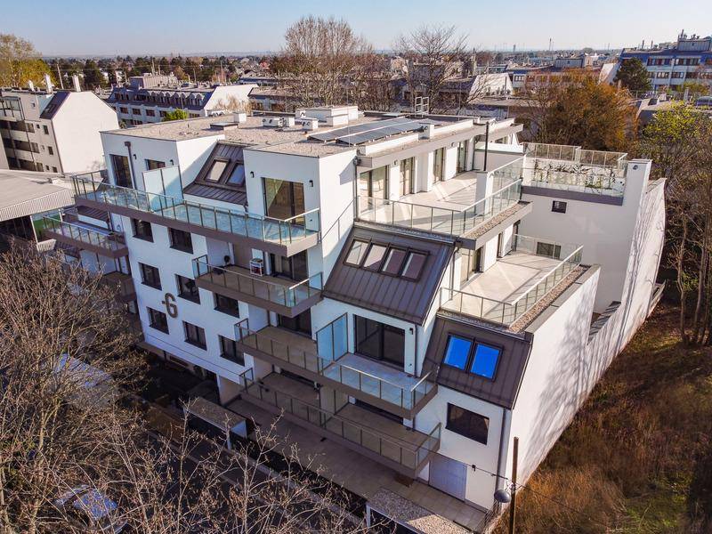 Moderne Wohnanlage mit mehreren Balkonen, Terrassen und Flachdach in städtischer Umgebung.