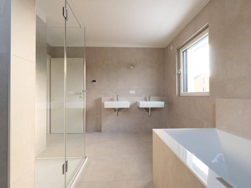 Modernes Badezimmer mit bodengleicher Dusche, zwei Waschbecken und Badewanne.