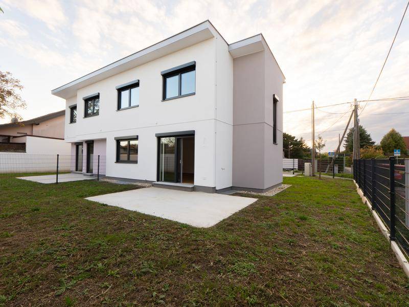Moderne Doppelhaushälfte von hinten mit Garten, Rasenfläche und Beton-Terrasse.