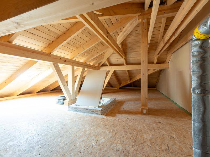 Geräumiger Dachboden mit sichtbaren Holzbalken und Dachschrägen, bereit zum Ausbau.