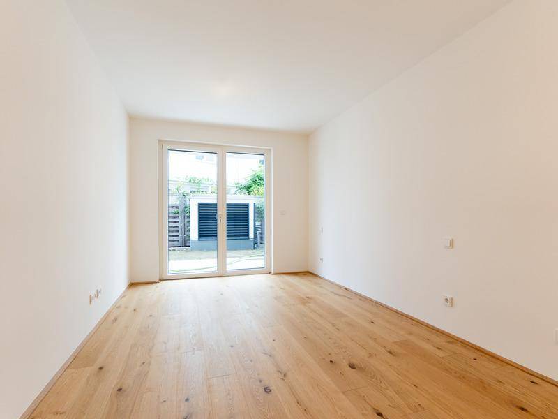 Helles Schlafzimmer mit Holzboden und direktem Zugang zu einem Außenbereich.