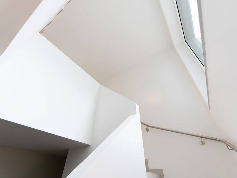 Detailansicht des modernen Treppenhauses mit hohen Decken und einem Oberlicht.