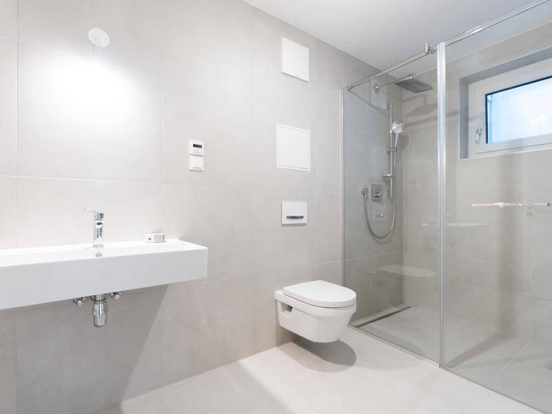 Modernes Badezimmer mit begehbarer Dusche, wandhängendem WC und Fenster.