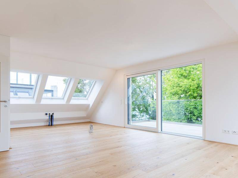Lichtdurchfluteter Wohnbereich mit Eichenparkett, Dachfenstern und Schiebetür zur Terrasse.