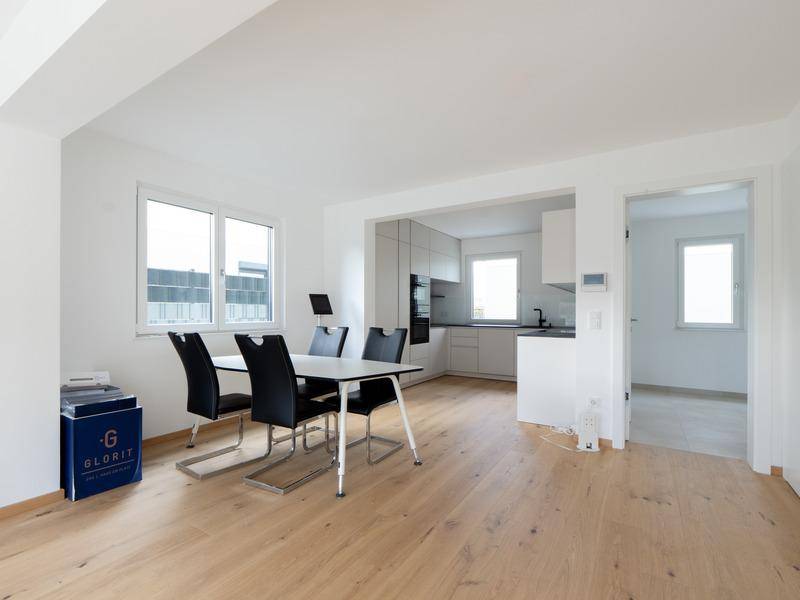 Offener Essbereich mit Holzboden und Blick auf die moderne Einbauküche.
