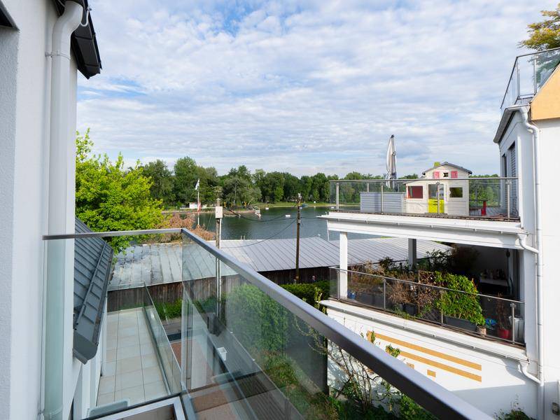 Balkon mit Glasgeländer und weitem Blick über andere Terrassen und das Wasser.