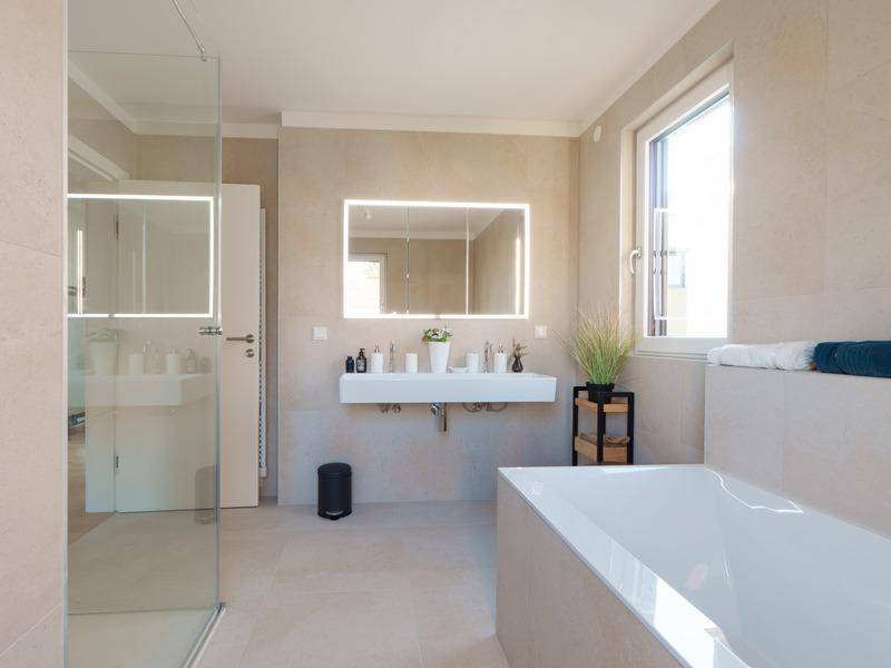 Modernes Badezimmer mit Badewanne, begehbarer Dusche und großem Spiegelschrank.