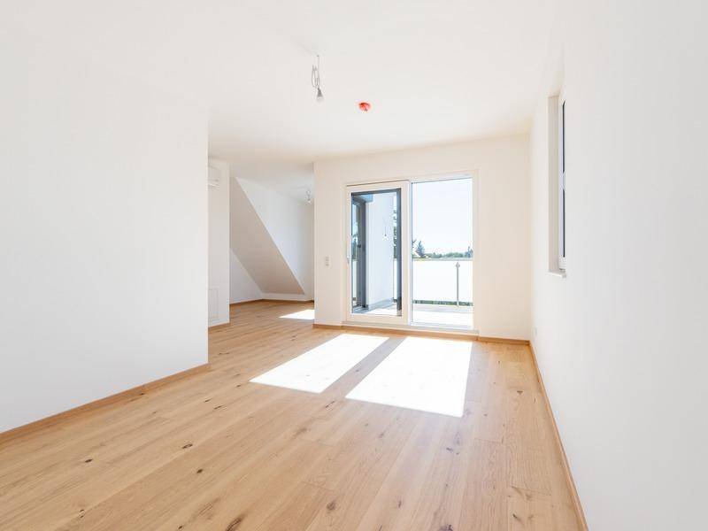Helles Schlafzimmer im Obergeschoss mit Holzboden und Zugang zu einem kleinen Balkon.