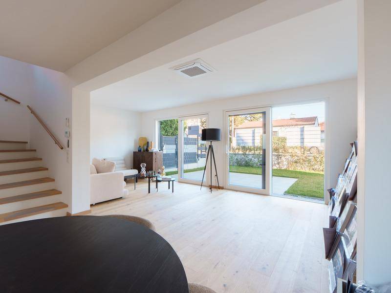 Gemütlicher Wohnbereich mit Sofa, Holzboden und direktem Zugang zum kleinen Garten.