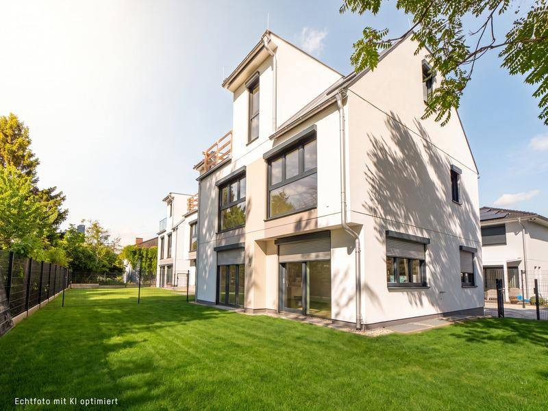 Moderne weiße Fassade eines Neubaus mit großen Fenstern und gepflegtem Rasen.