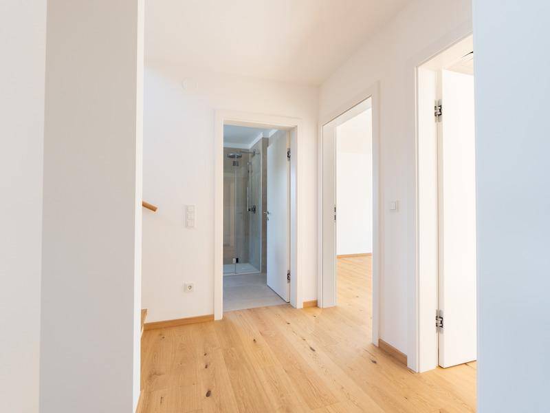 Heller Flur mit Holzfußboden und Zugang zu Badezimmer und weiteren Räumen.