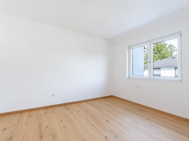 Leeres Zimmer mit hellem Holzfußboden und Fenster, ideal als Schlafzimmer.