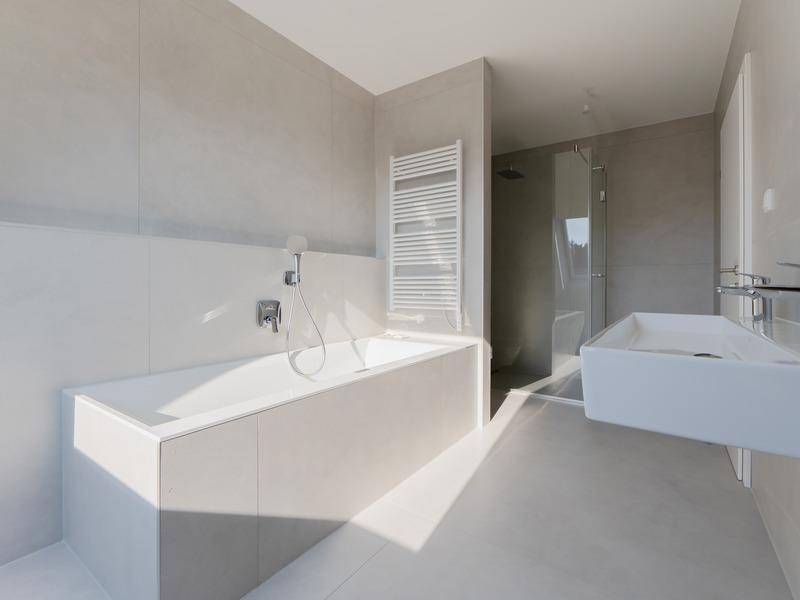 Modernes Badezimmer mit Badewanne, begehbarer Dusche, Doppelwaschbecken und grauen Fliesen.