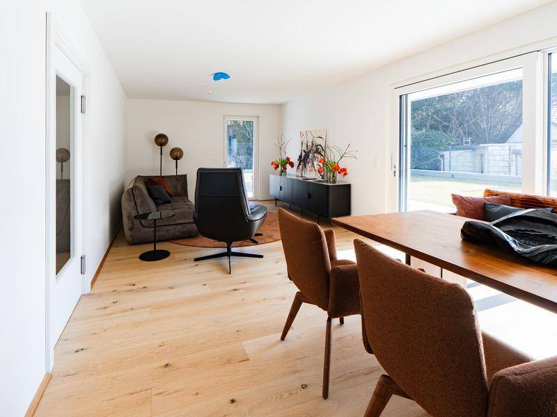 Geräumiger Wohnbereich mit Sofa und Sessel, offen zum Essbereich und zur Küche, mit Zugang zum Garten.