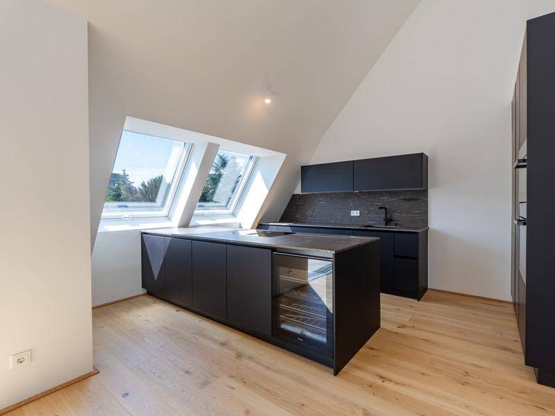 Moderne Küche mit dunklen Schränken, Kücheninsel und großen Dachfenstern in Dachschräge.