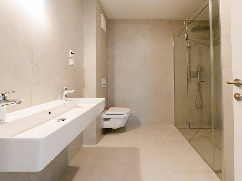 Modernes Badezimmer mit Doppelwaschbecken, wandhängendem WC und begehbarer Dusche.
