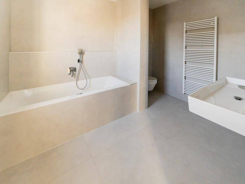 Modernes Badezimmer mit Badewanne, Einzelwaschbecken, wandhängendem WC und Handtuchheizkörper.