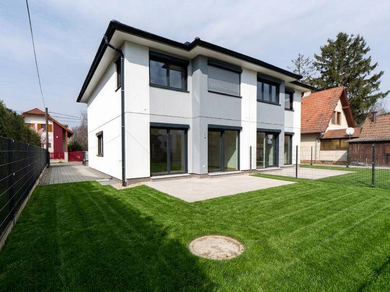 Modernes Einfamilienhaus mit gepflegtem Rasen und einer Terrasse im Garten.
