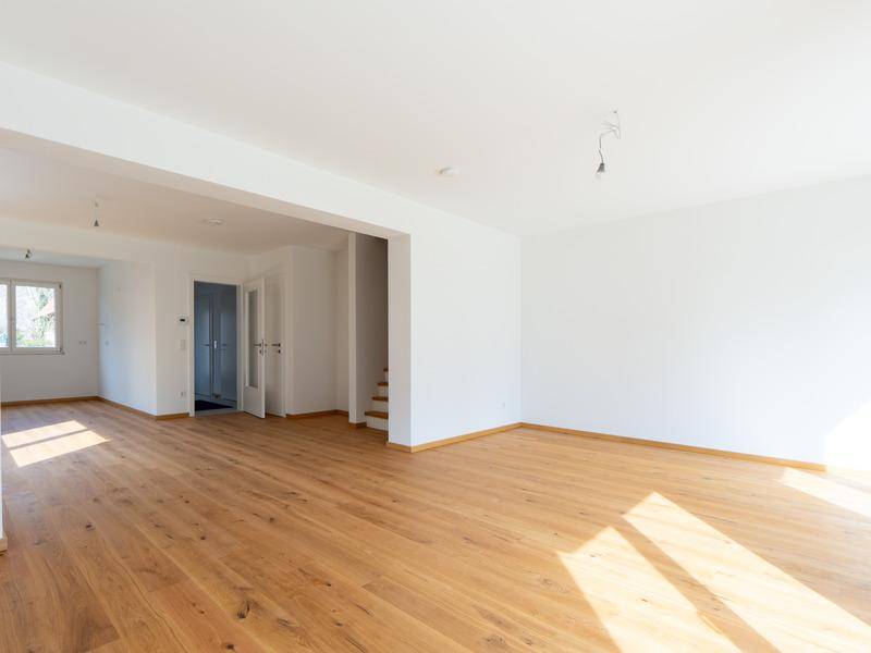 Geräumiger, heller Wohnbereich mit Holzboden und Zugang zu weiteren Räumen.