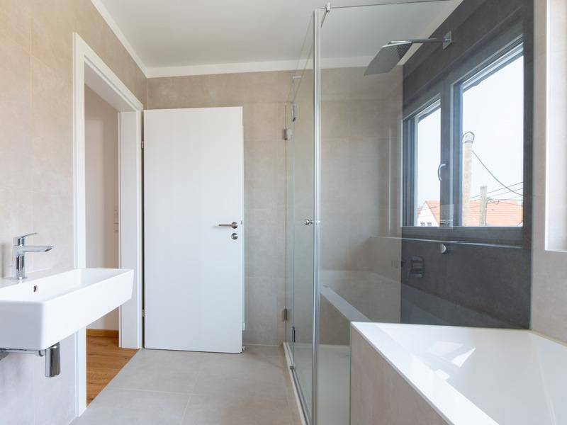 Modernes Badezimmer mit begehbarer Dusche, Badewanne, Einzelwaschbecken und Fenster.